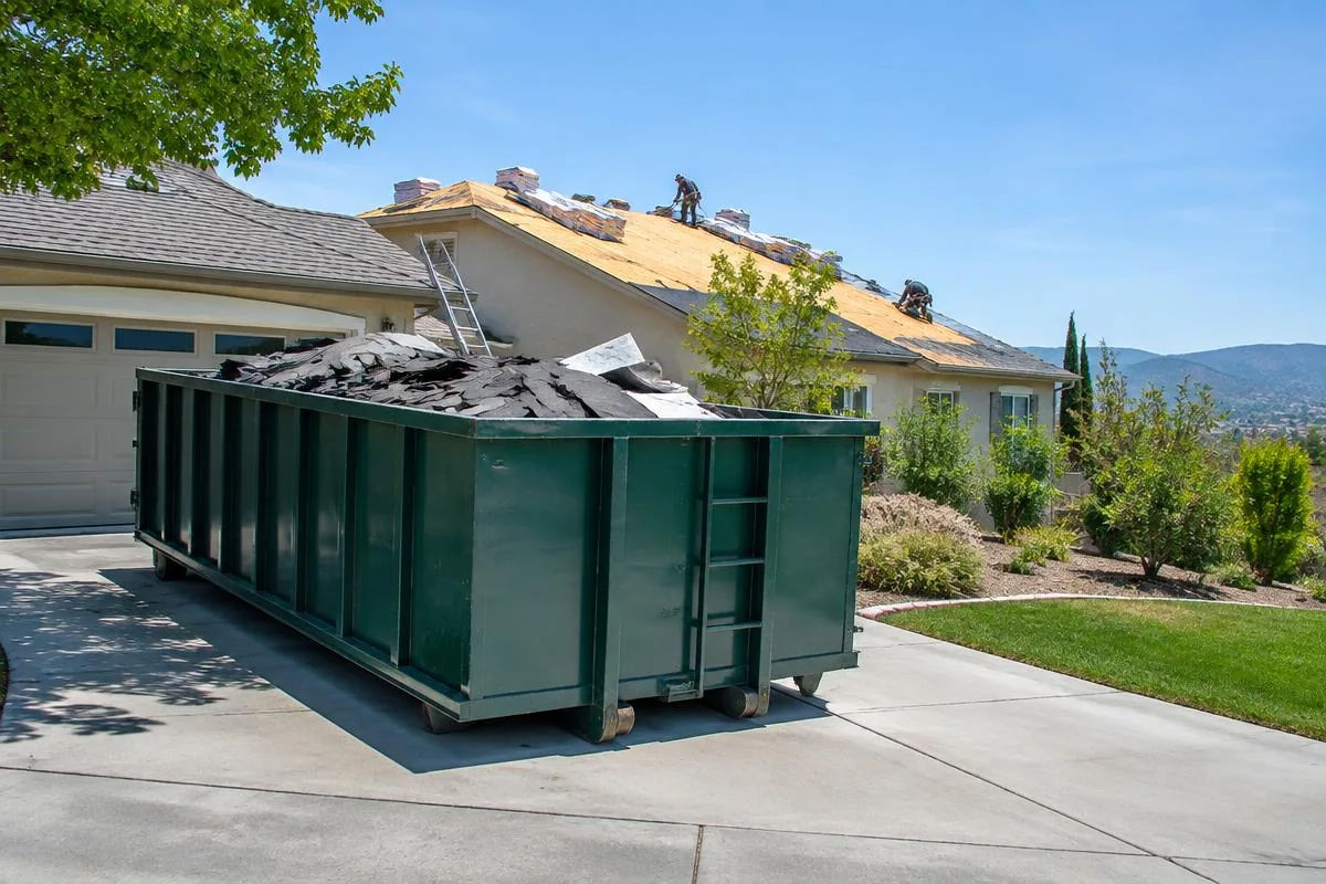 Roofing debris contained in a roll-off dumpster